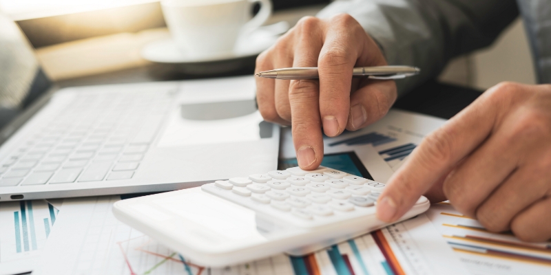 Professional accountant's hand with pen calculating financial data.